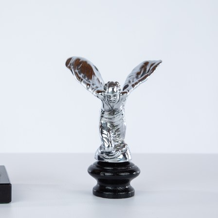 A chrome Spirit of Ecstasy radiator mascot on a black base.
